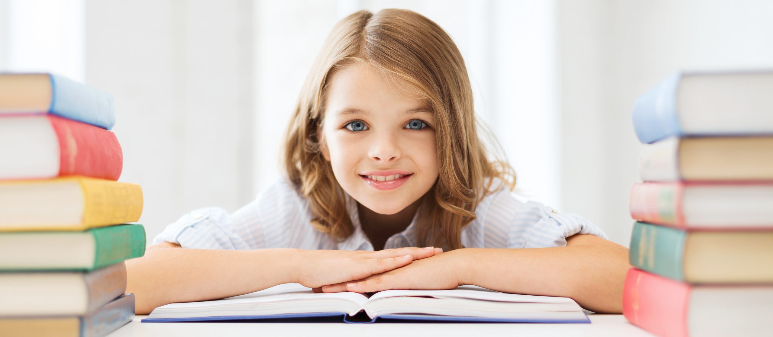 lächelndes kleines Studentenmädchen mit vielen Büchern